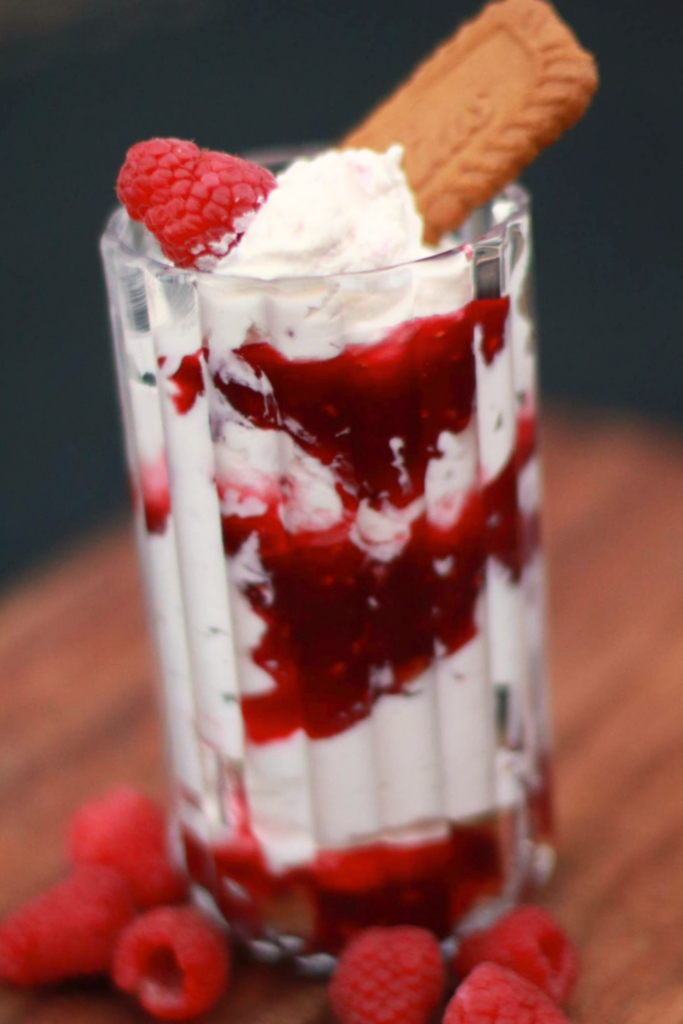 Close up of raspberry parfait layers with whipped cream and cookie crumble topping