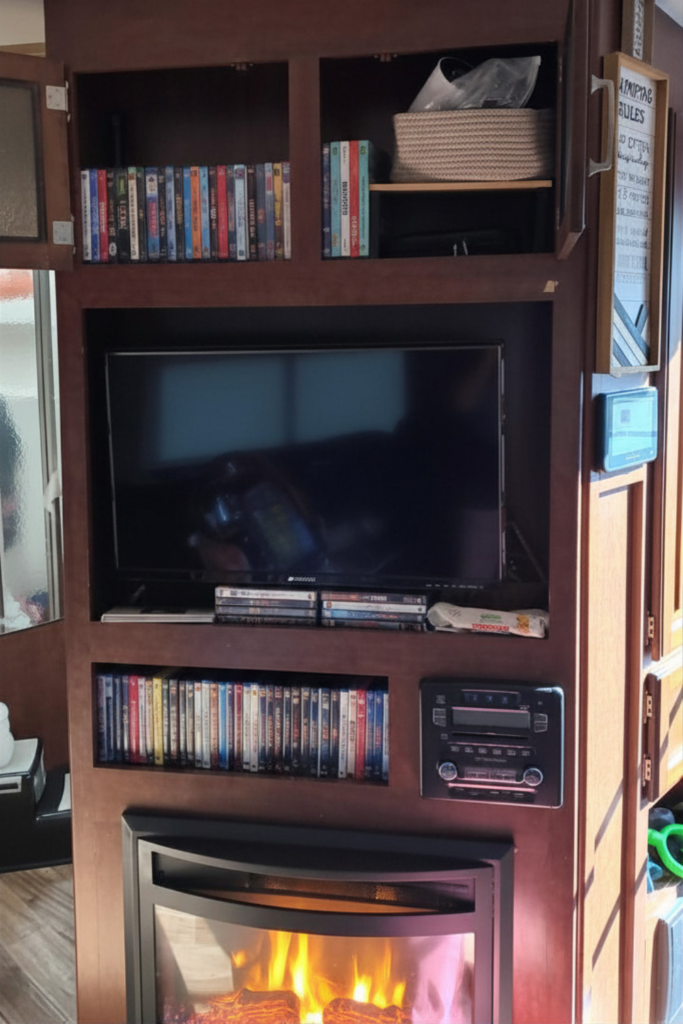 29 Genius RV Storage Ideas for Small Spaces with Kids 11 DIY RV storage hacks showing DVD organization above the fireplace and TV to save space inside the RV