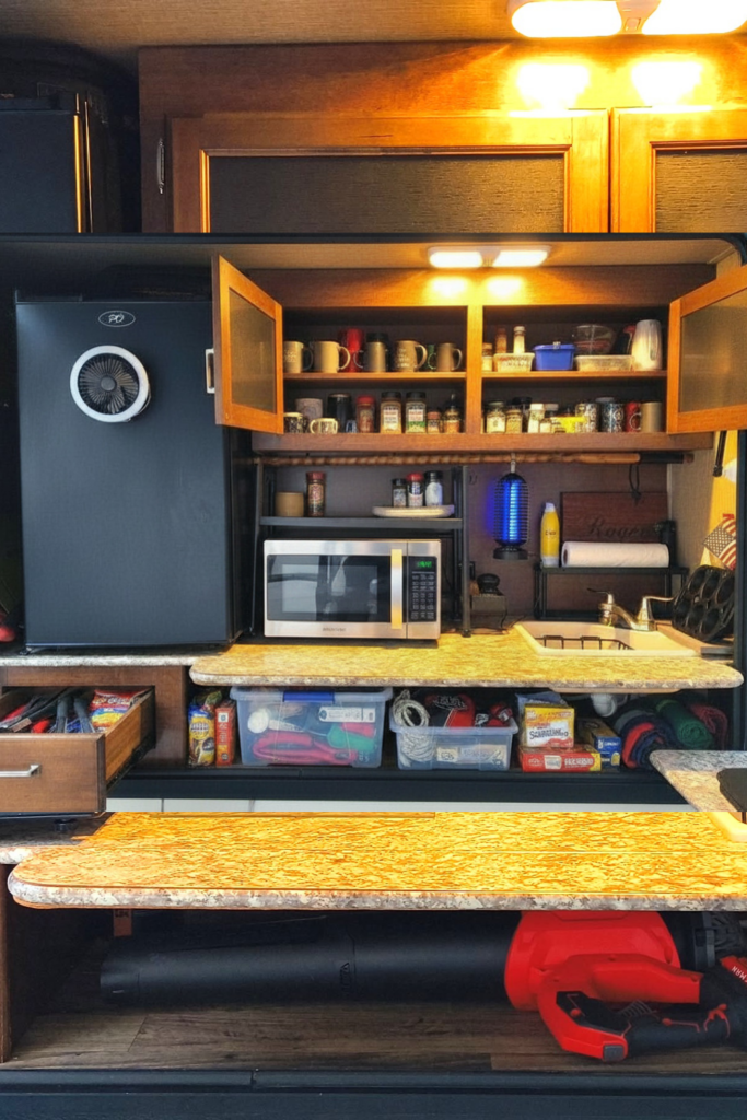 29 Genius RV Storage Ideas for Small Spaces with Kids 7 RV storage ideas exterior featuring organized outdoor kitchen spices, clear storage bins, camping supplies, and a leaf blower
