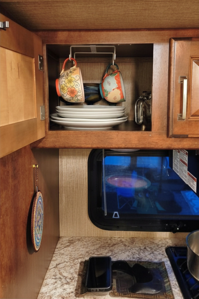 29 Genius RV Storage Ideas for Small Spaces with Kids 13 RV storage ideas interior with hanging cup storage inside cabinets and organized plate storage to maximize cabinet space