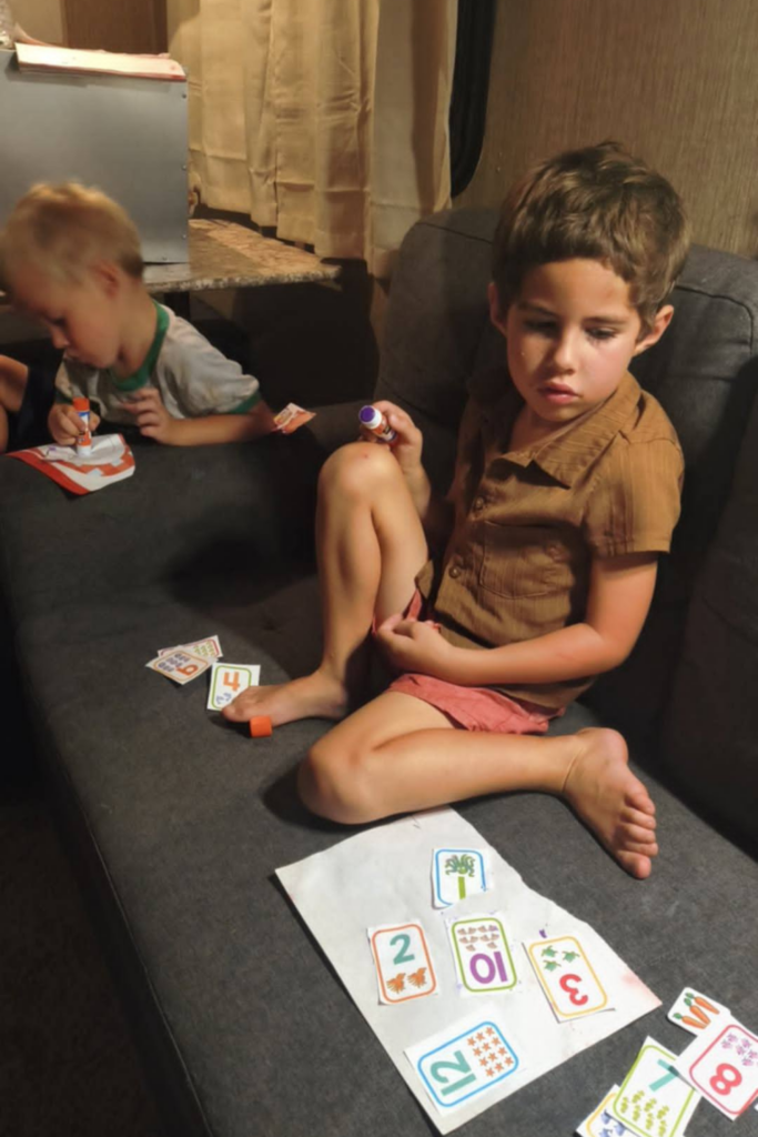 RV Activities for Kids: 50+ Amazing Ideas for Fun Family RV Living 5 Children practicing homeschool worksheets with numbers, shapes, and cutting skills as indoor RV activities for kids