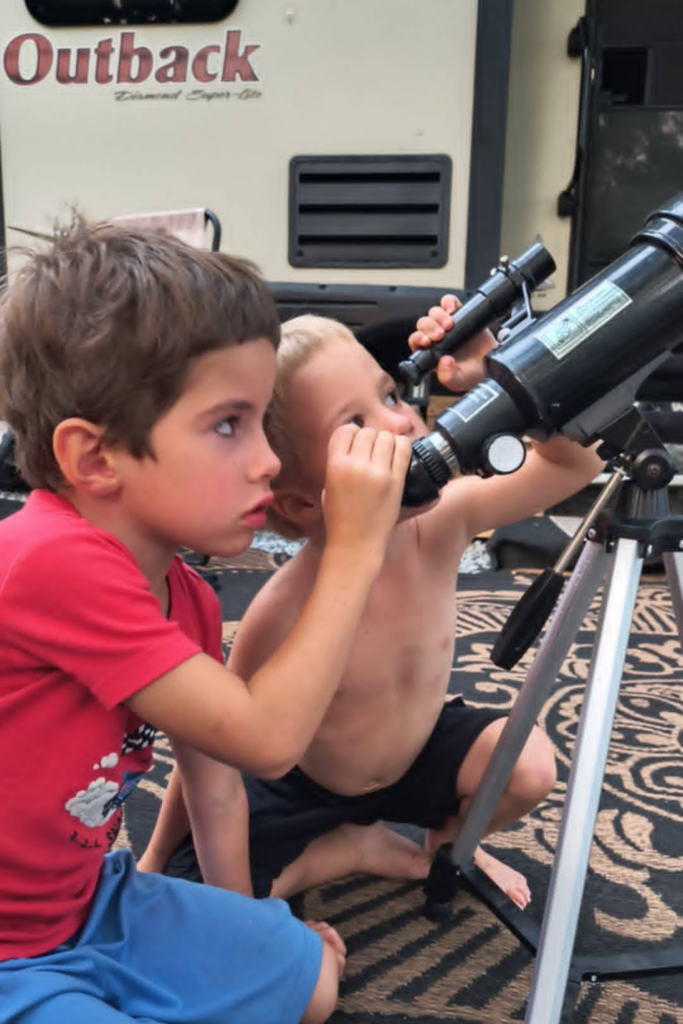 Children using a telescope for stargazing as one of the best nighttime camping activities for kids