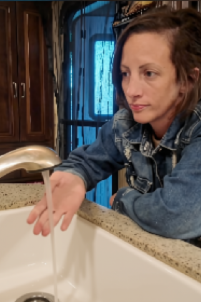 Trisha testing hot water at the RV kitchen sink with water running